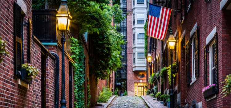 an alley in a Massachusetts street with cobblestone pavement and an american flag hanging from a brick building