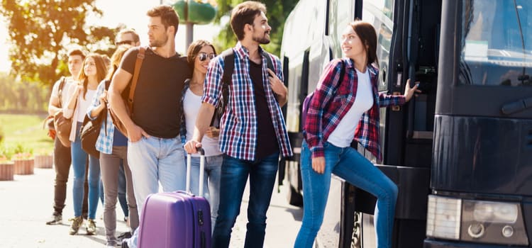 charter bus passengers smile as they load onto a bus