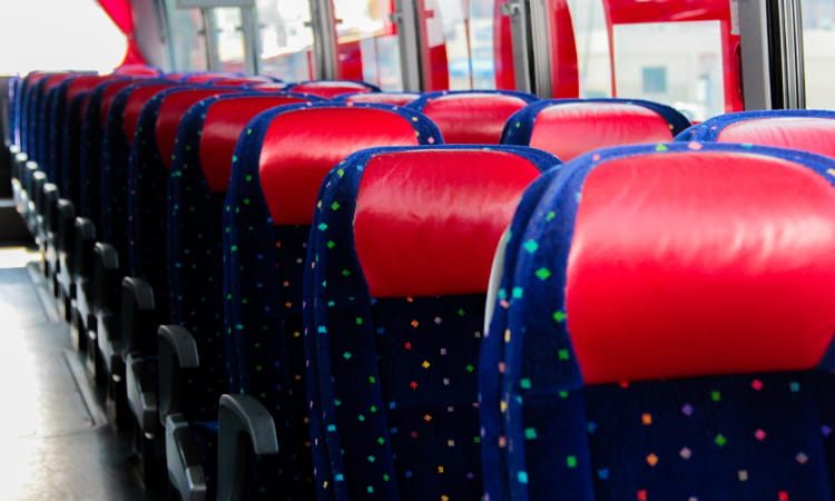 rows of seats inside an empty charter bus, all blue with red headrests