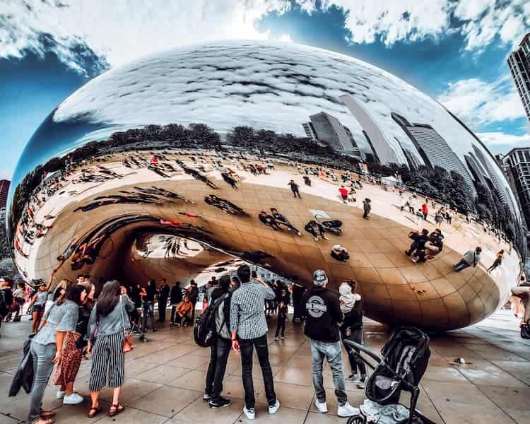 visitors view their reflections in the cloud gate at millennium park in chiago