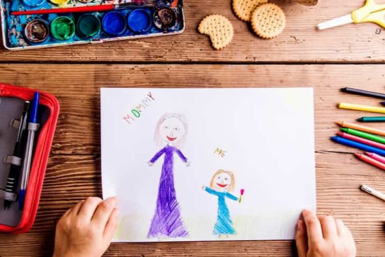 Child drawing picture of her and her mother