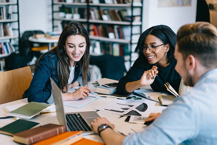 A group of college-aged students work on a project in a study lounge