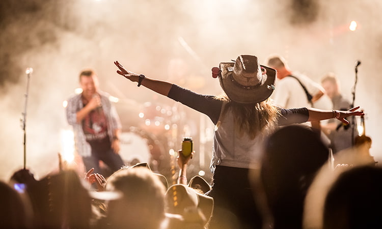 A country music fan cheers at a concert while wearing a cowboy hat