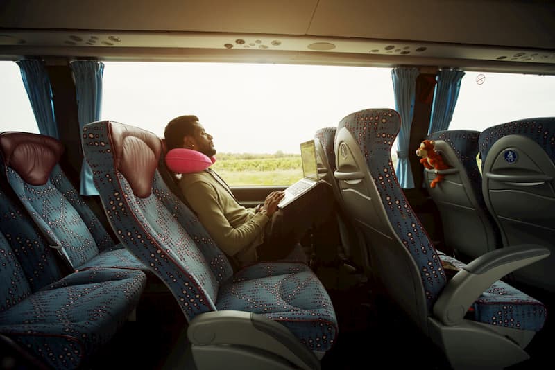 portrait of man relaxing on charter bus with computer on lap