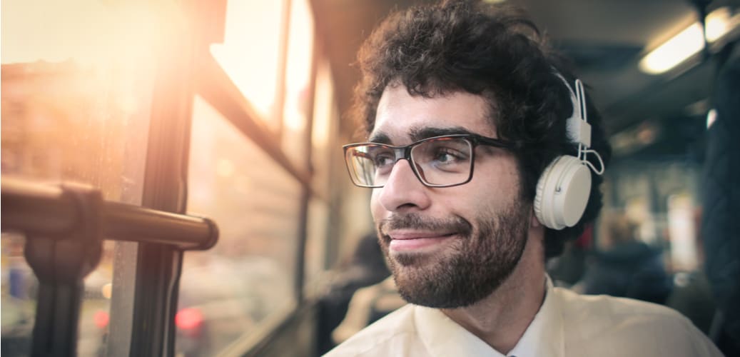 a man looks out the window of a shuttle bus while wearing headphones