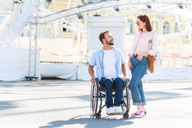 A man in a wheelchair and a woman enjoying a theme park