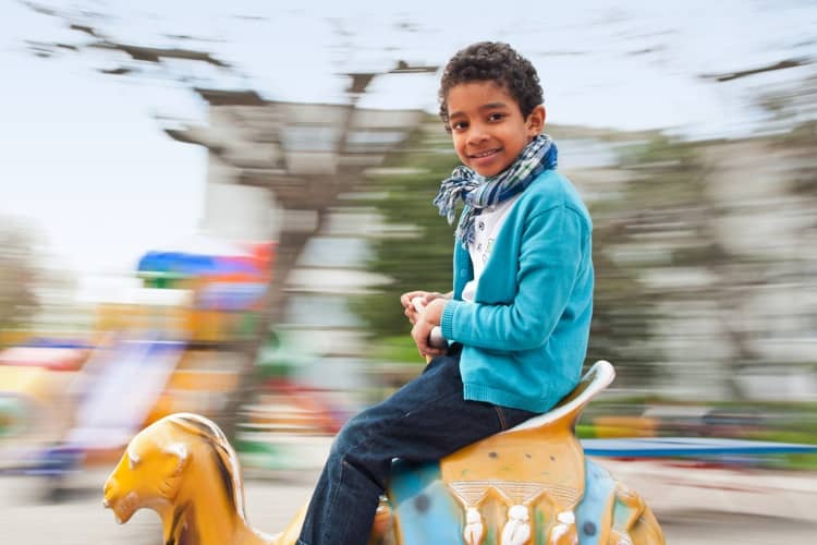 A young child smiling on a theme park ride