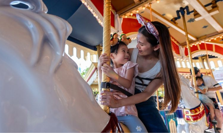 Mother and child wearing Mickey Mouse ears riding on a carousel