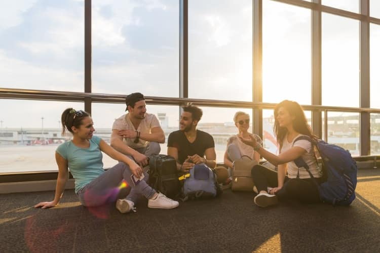 Friends sitting on floor at airport terminal