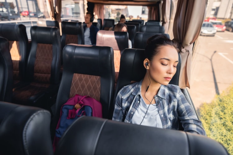 a woman sleeps on a seat inside a charter bus