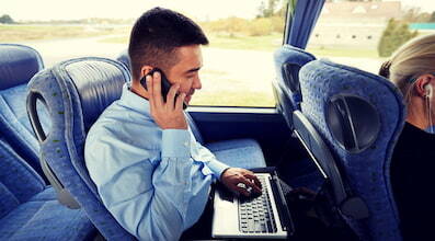 an employee takes a phone call and types on a laptop while riding a bus