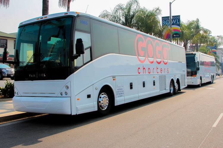 two white buses with "gogo charters" logos parked by a sidewalk