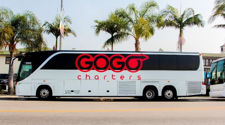 A GOGO charter bus parked by trees