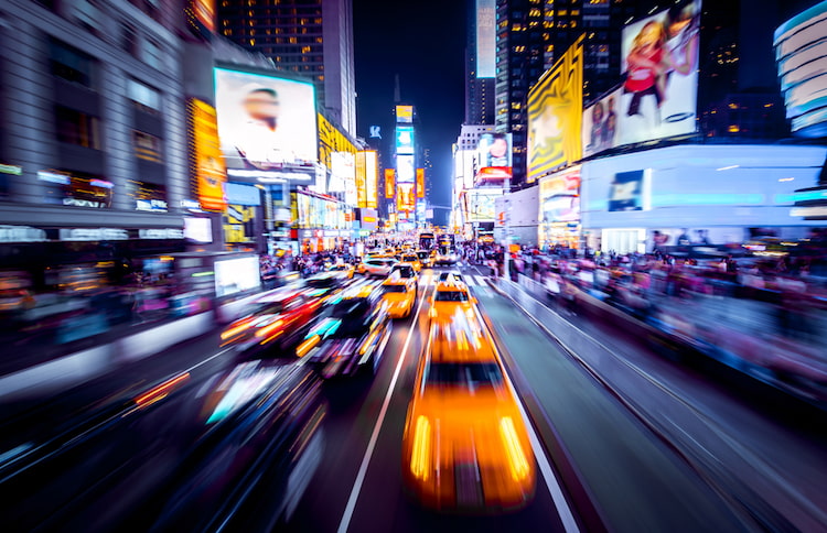 busy cars on a street in the middle of times square at night