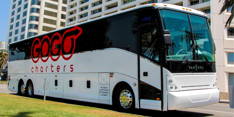 a charter bus with the "gogo charters" logo, parked outside of a building