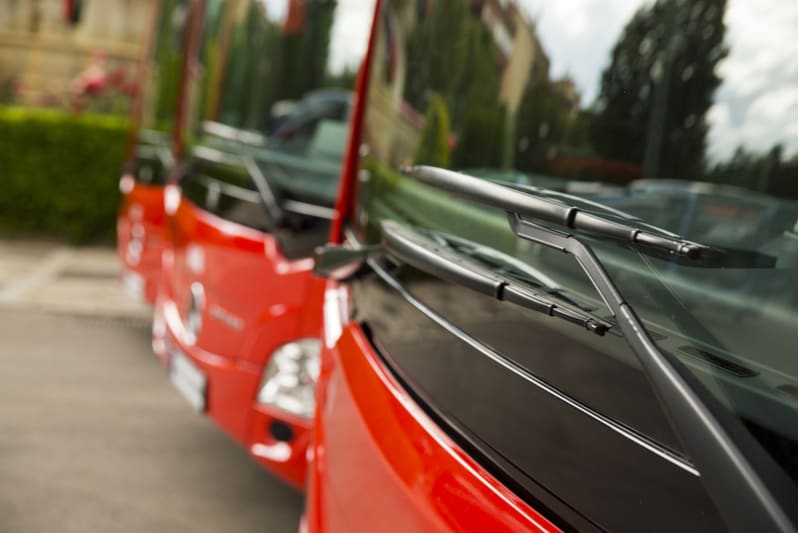 the front of three red charter buses parked next to one another