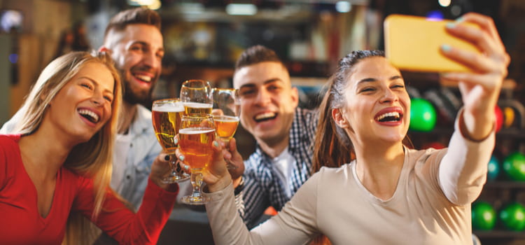 friends cheers their beer glasses and smile to take a selfie