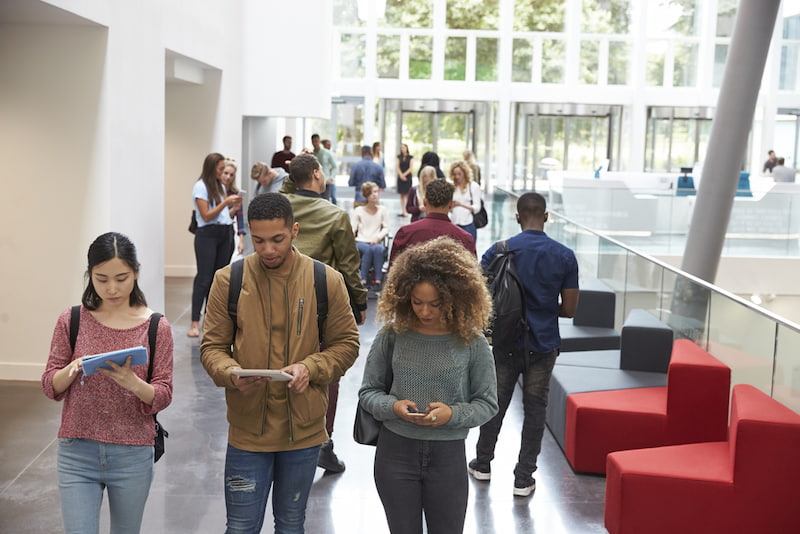 students walk through a large open classroom building