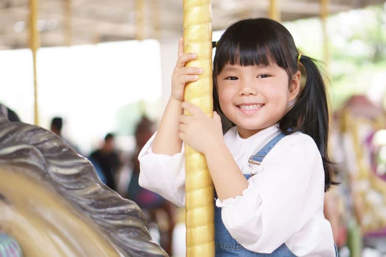 Little girl riding carousel horse