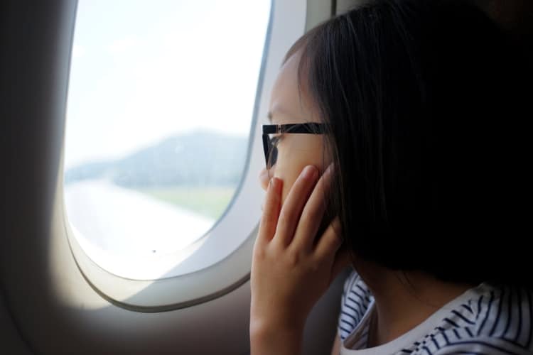 Little girl gazing out window of plane