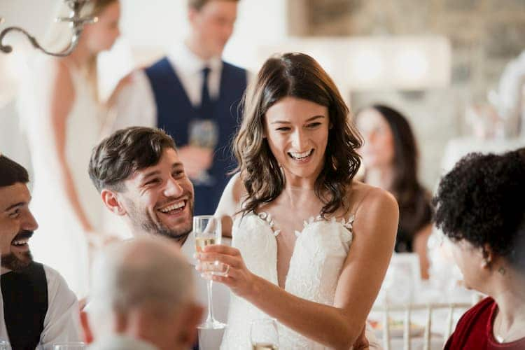 Bride sitting on groom's lap at wedding reception