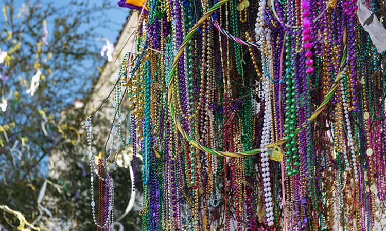 hundreds of plastic bead necklaces hang from a railing at a Mardi Gras celebration