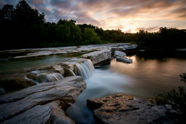 a beautiful small waterfall flows over rocks in a river