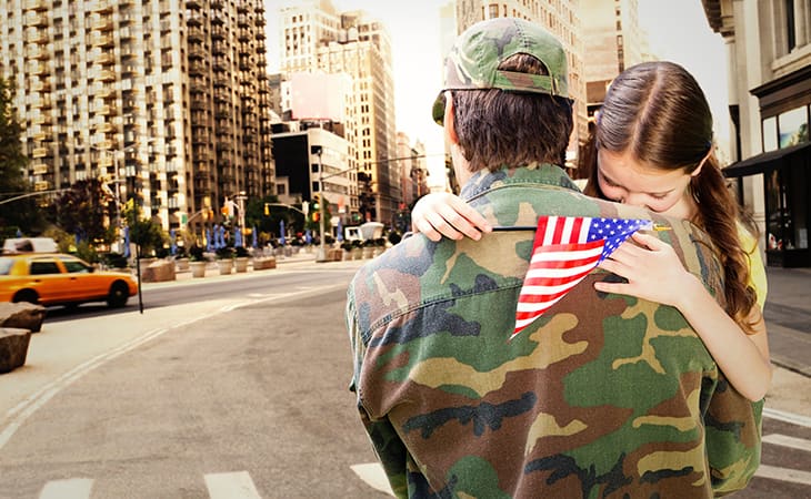 A father in military clothes carries his daughter through New York City