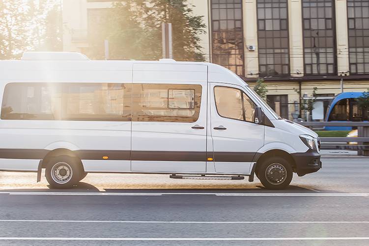 A minibus rides on a city road on a sunny day