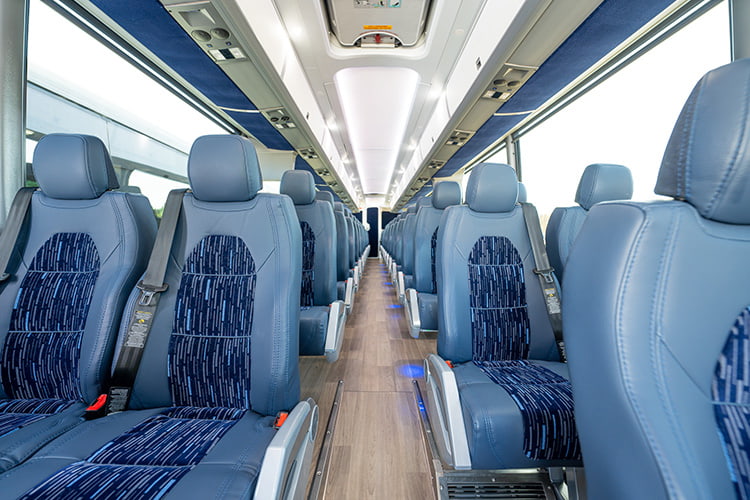 Large motorcoach interior with rows of seats and overhead storage