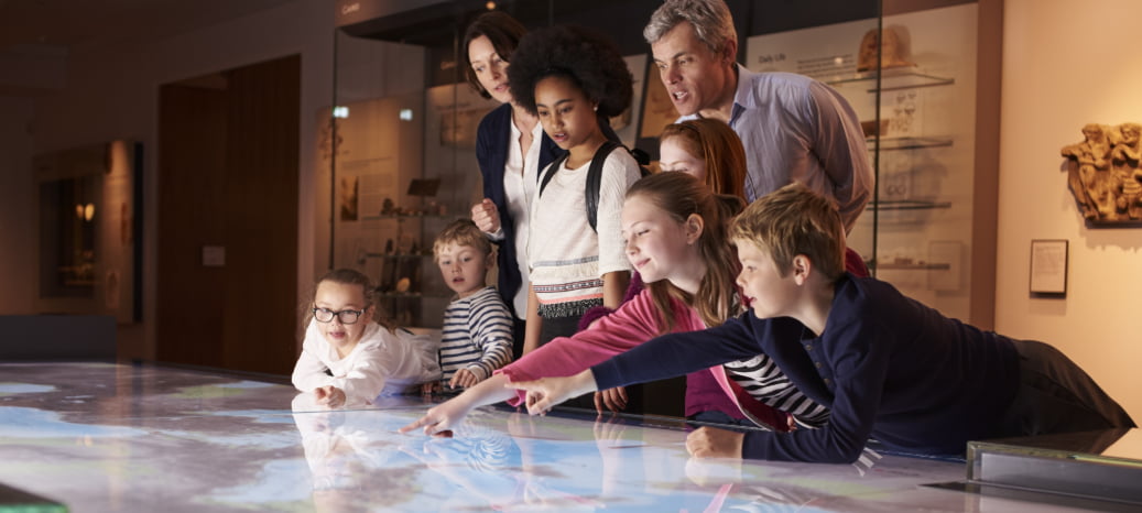 a group of school-age children tour a museum with a chaperone and tour guide