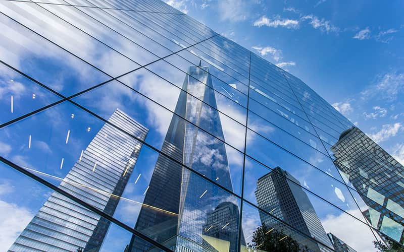 the Freedom Tower in NYC reflected in a building at the 9/11 Memorial and Museum