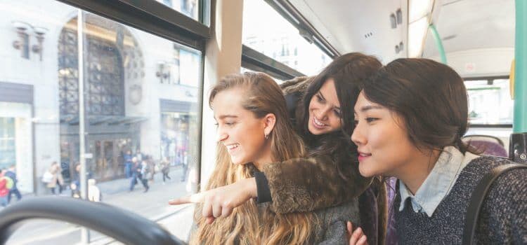 Three friends on a charter bus in New York City looking out the window