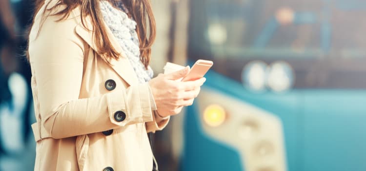 A person holding a phone waiting on a bus