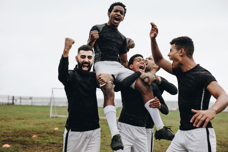 sports players hold up their teammate on their shoulders and cheer