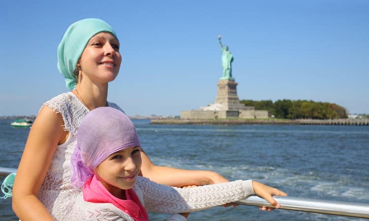 mother and daughter on ferry with statue of liberty behind them