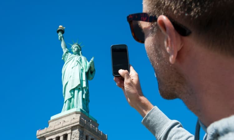 man taking a photo of the statue of liberty with a smart phone