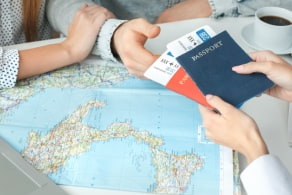 a travel agent hands a passport and ticket to someone