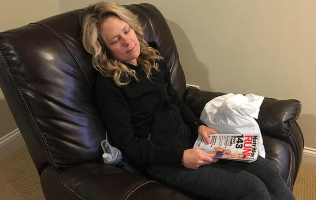 Woman sleeping in armchair with running magazine