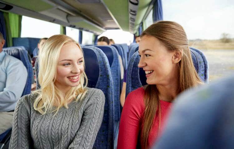 Two women sitting on charter bus and smiling