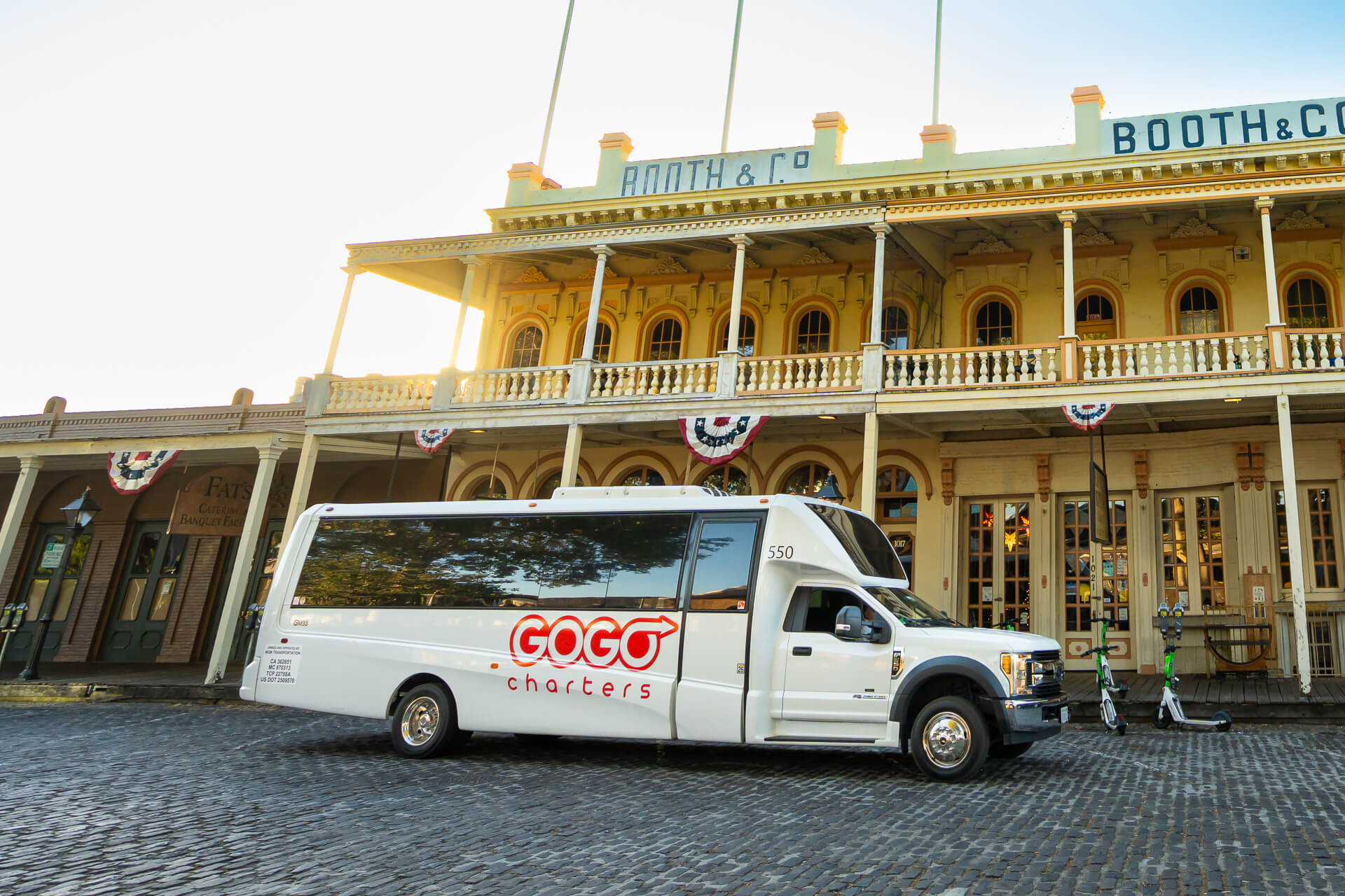 Minibus with GOGO Charters logo on parked in front of a two story building