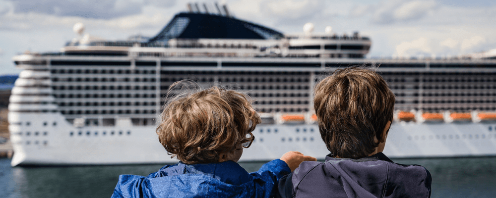 two children look at a cruise ship