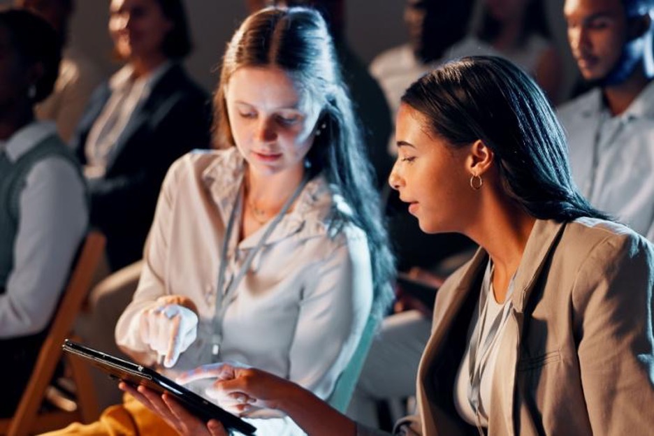 two corporate event attendees study notes on an ipad