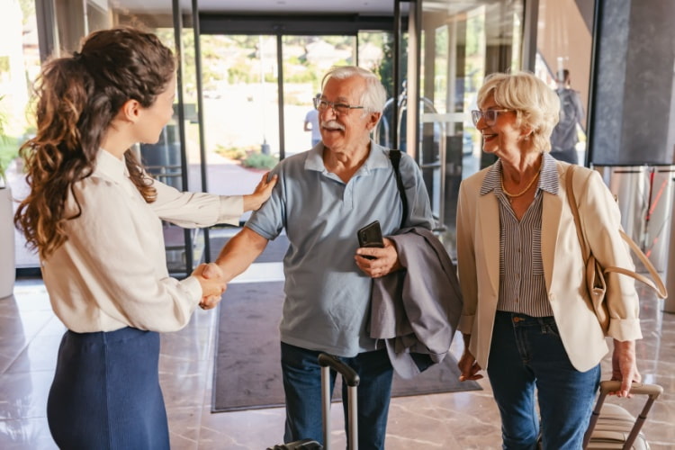 an older couple in the lobby of a hotel is greeted by an employee