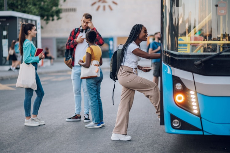 a young woman boards a charter bus while her friends chat nearby