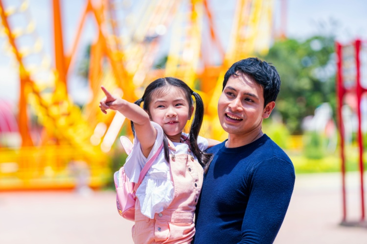 a father holds his daughter at a theme park