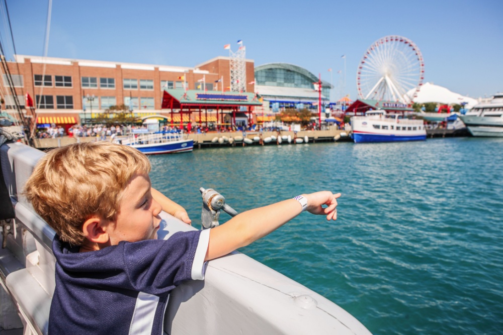 a boy looks out at navy pier from a river boat
