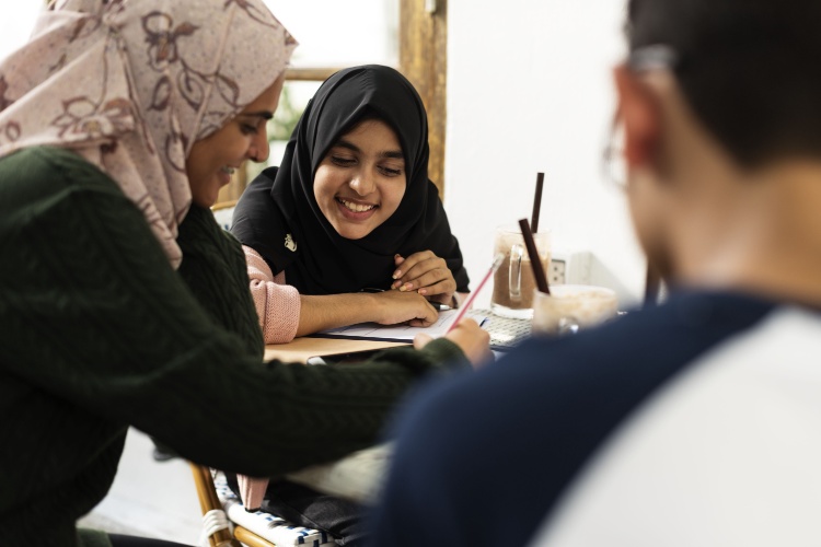 two young girls in hijabs studying together