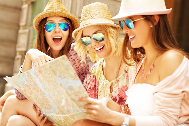 three women on vacation look at a map together