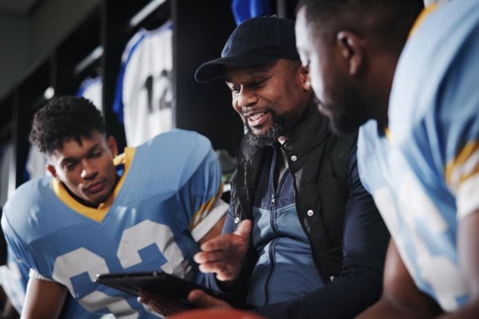 a coach smiles while describing plays to players